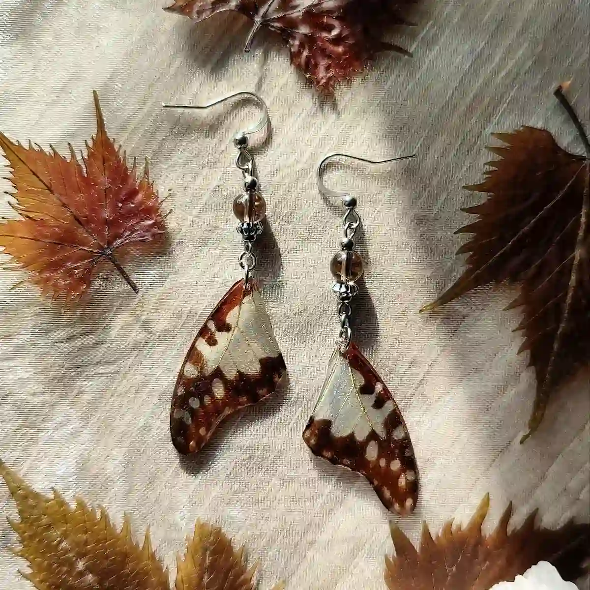 Boucles d'oreilles pendantes avec ailes de papillon Graphium angolanus dans résine et quartz fumé.