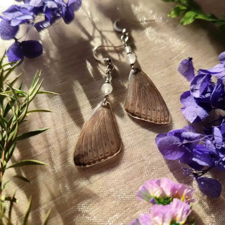 Boucles d'oreilles pendantes avec ailes de papillon Sevenia pechueli dans résine, accompagnées de labradorite et pierre de lune.