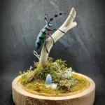 Cloche entomologique avec diorama montrant un longicorne Diastocera wallichi tricincta, décoré de bois, mousse, lichen et pierre d'opale.