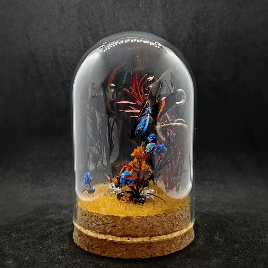 Cloche entomologique avec diorama montrant un papillon Milionia fulgida, décoré de pierre d'obsidienne.