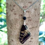 Collier avec pendentif en résine contenant une aile de papillon Papilio machaon, décoré de pierre d'obsidienne.