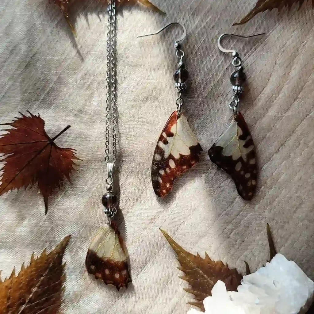 Collier avec pendentif en résine contenant une aile de papillon Graphium angolanus et du quartz fumé.